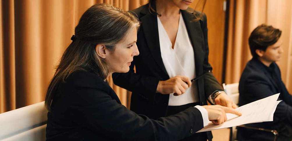 Två kvinnor diskuterar ett dokument.
