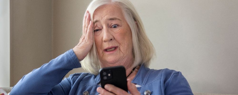 Kvinna som sitter och tittar i sin mobiltelefon